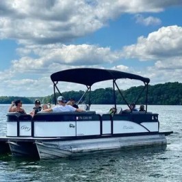 Group on pontoon boat in a lake under cloudy sky.
