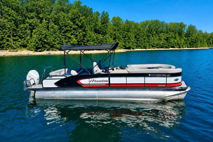 Pontoon boat on a lake with forested shoreline in the background.